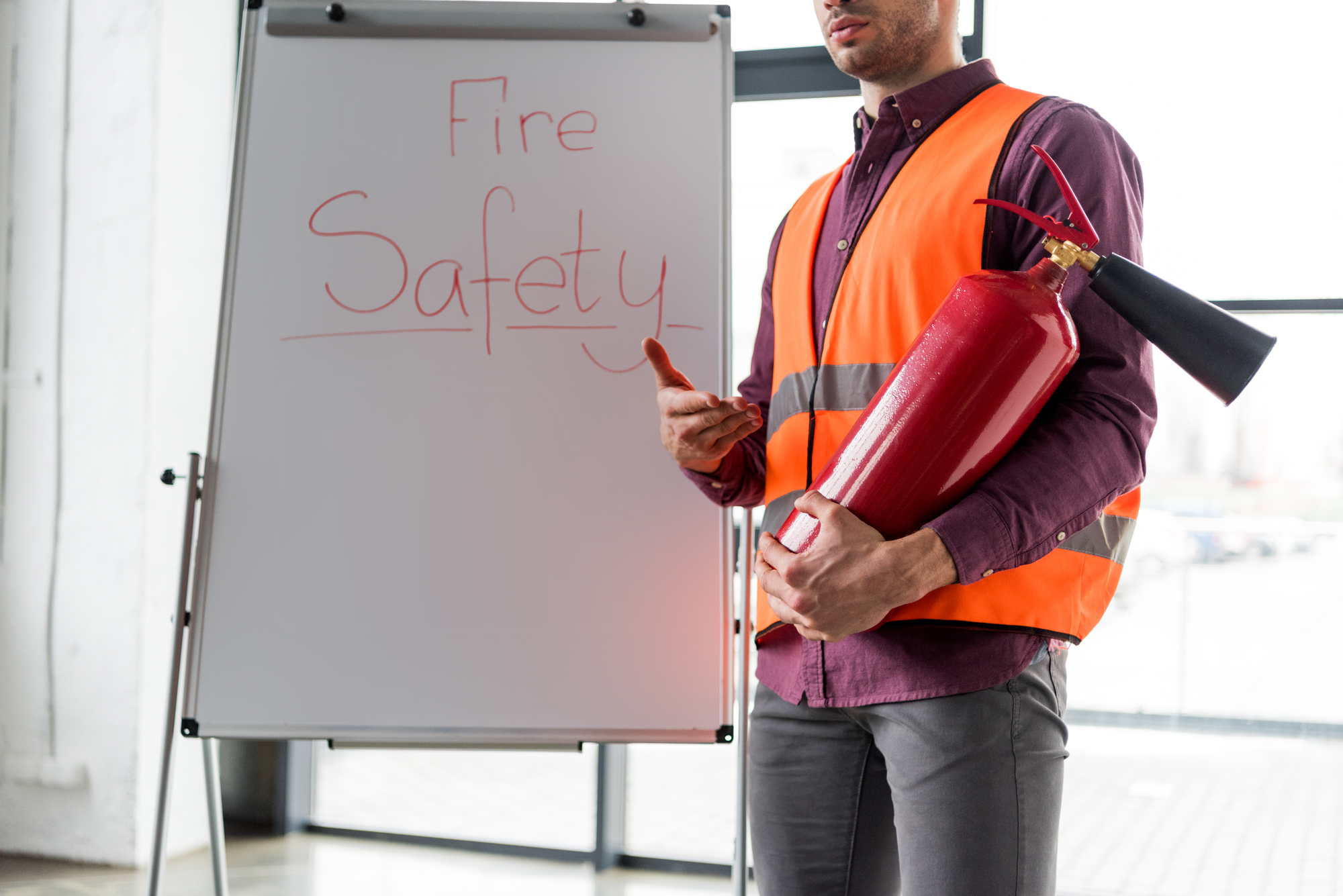 A man holding a fire extinguisher and is wearing a safety gear