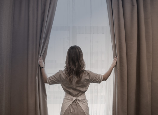 The woman opening the curtains
