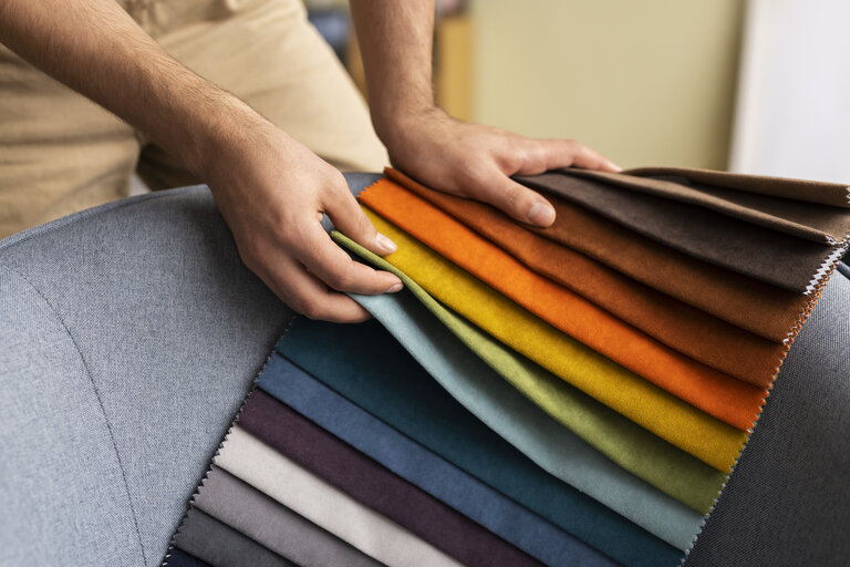 Mans hands picking out fabrics out of some colorful options